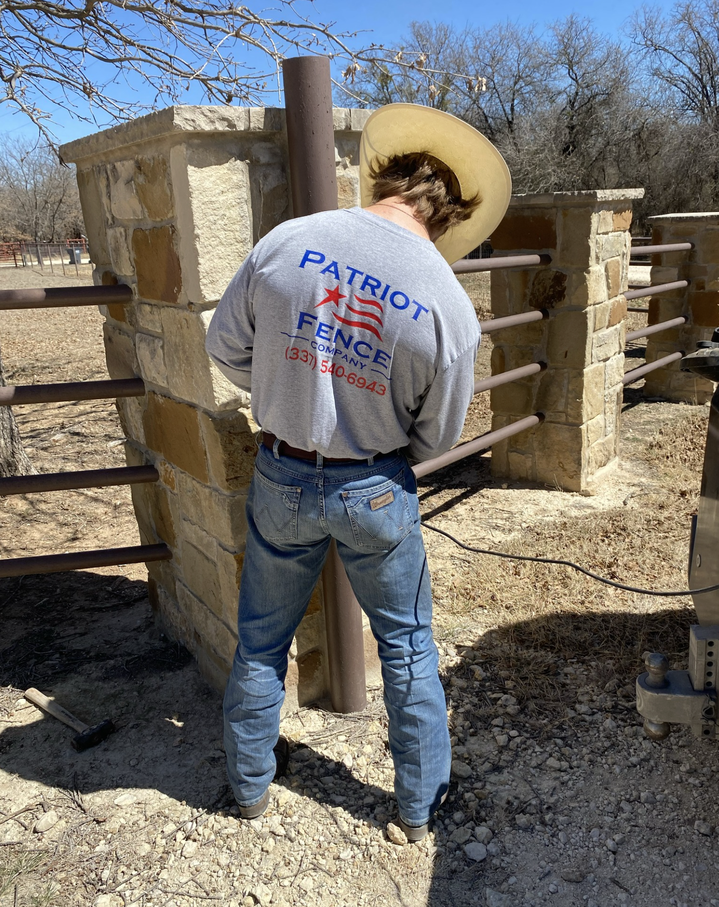 Patriot Fence Company crew member at a stone and pipe fence project