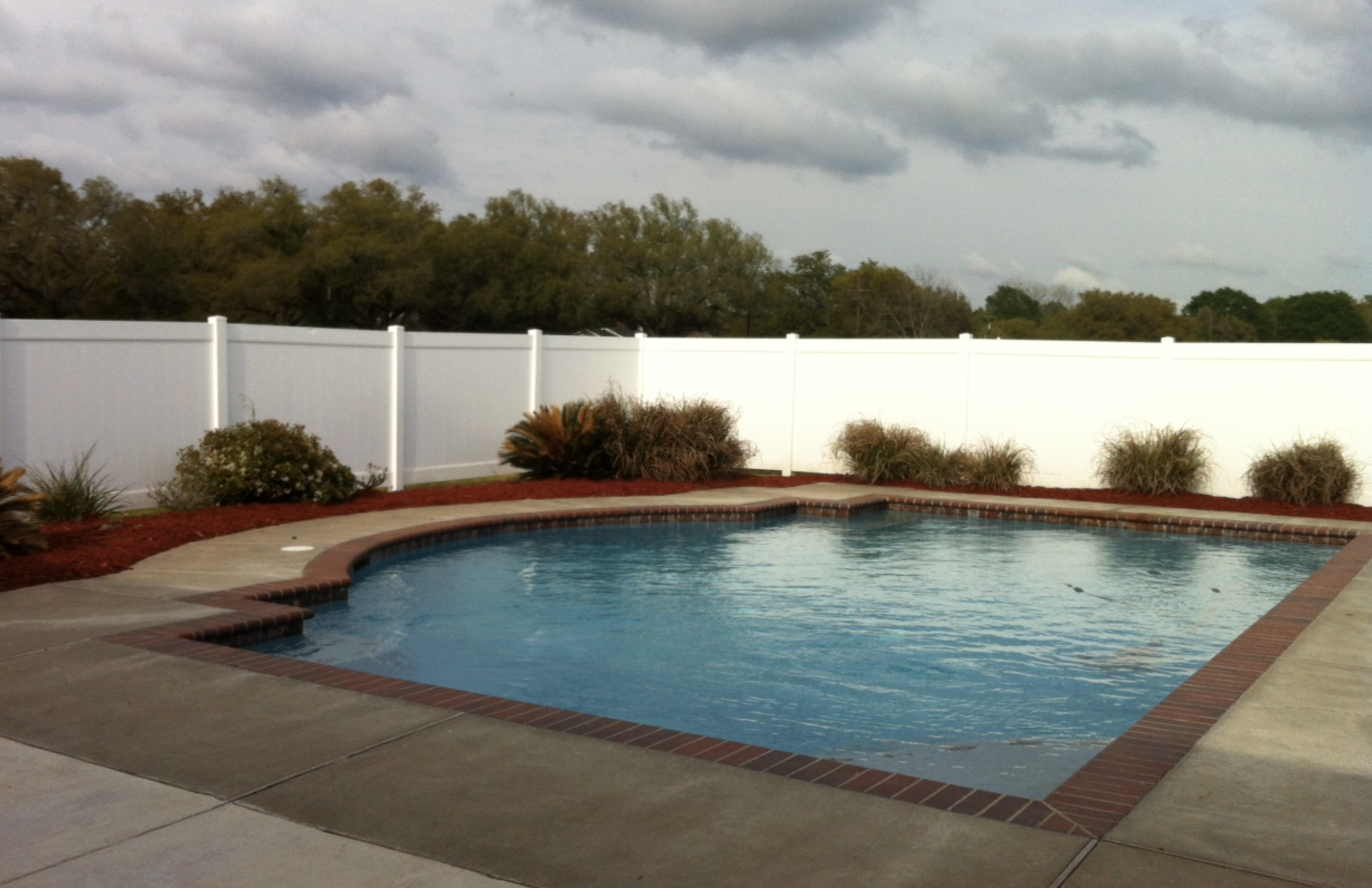 White vinyl privacy fence enclosing a pool backyard