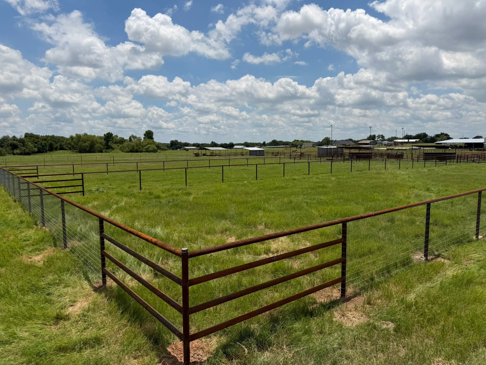 Pipe and wire cattle pen fencing on an open Texas pasture