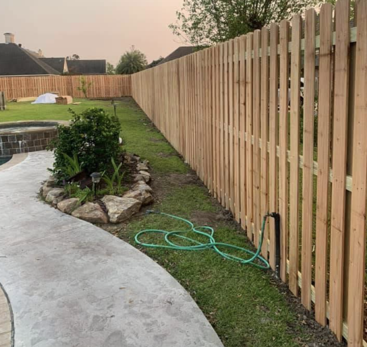 Wood picket fence installed around a backyard pool area